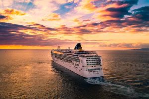 Cruise ship moving towards sunset horizon
